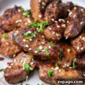 Delicious Pork Liver: Easy Recipes & Expert Tips 6 Grilled beef pieces garnished with sesame seeds and chopped parsley share the spotlight on a round ceramic plate, complemented by succulent slices of pork liver.