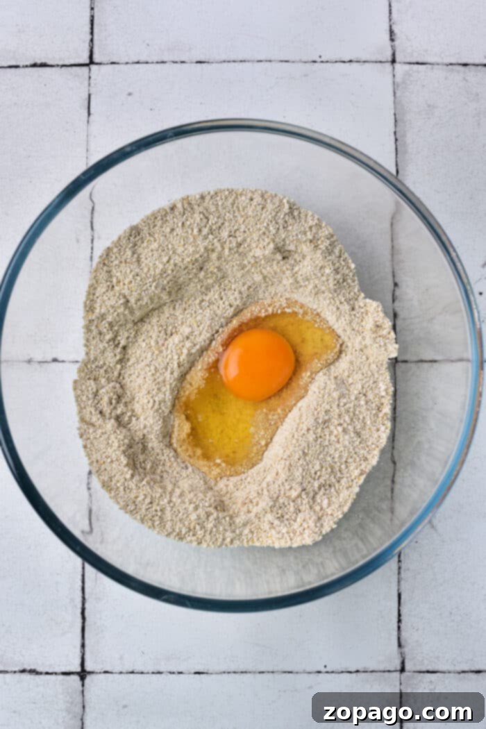 Matzo Ball Explained: Definition and Easy Recipe 4 A glass bowl with matzo meal and a cracked egg in the center, representing the start of matzo ball preparation.