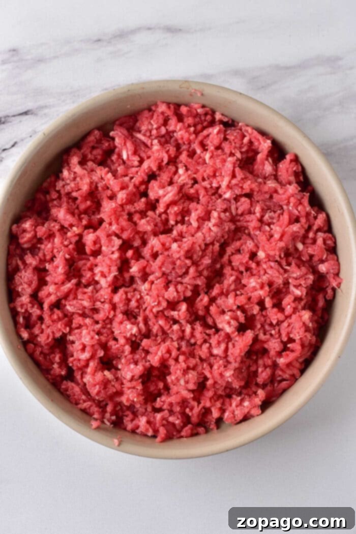 Cooking Ground Beef to Perfection 3 A bowl filled with raw ground meat rests on a marble surface, inviting you to ponder how long to cook ground beef for the perfect savory dish.