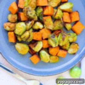 Crispy Air Fryer Brussels Sprouts and Sweet Potatoes 7 A delicious plate featuring perfectly roasted Brussels sprouts and sweet potatoes sits invitingly, with a fork poised beside it, ready to dive into this wholesome delight.