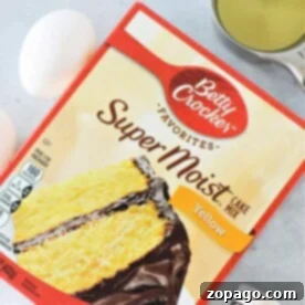 Next-Level Box Cakes Secret Tips for a Homemade Taste 9 Box of Betty Crocker yellow cake mix with eggs, oil, and vanilla extract on a gray surface, ready for some creative box cake mix hacks.