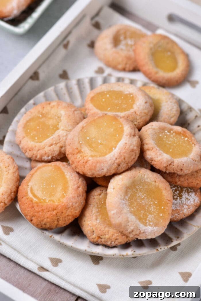 Zesty Lemon Curd Delights 8 A close-up of a single lemon curd cookie, showcasing its perfect thumbprint indentation filled with bright, zesty lemon curd, ready to be enjoyed.