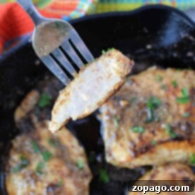A fork holds a slice of cooked chicken breast over a sizzling cast iron skillet.