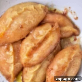 A plate with six golden-brown sweet potato dumplings rests on a pristine white surface.