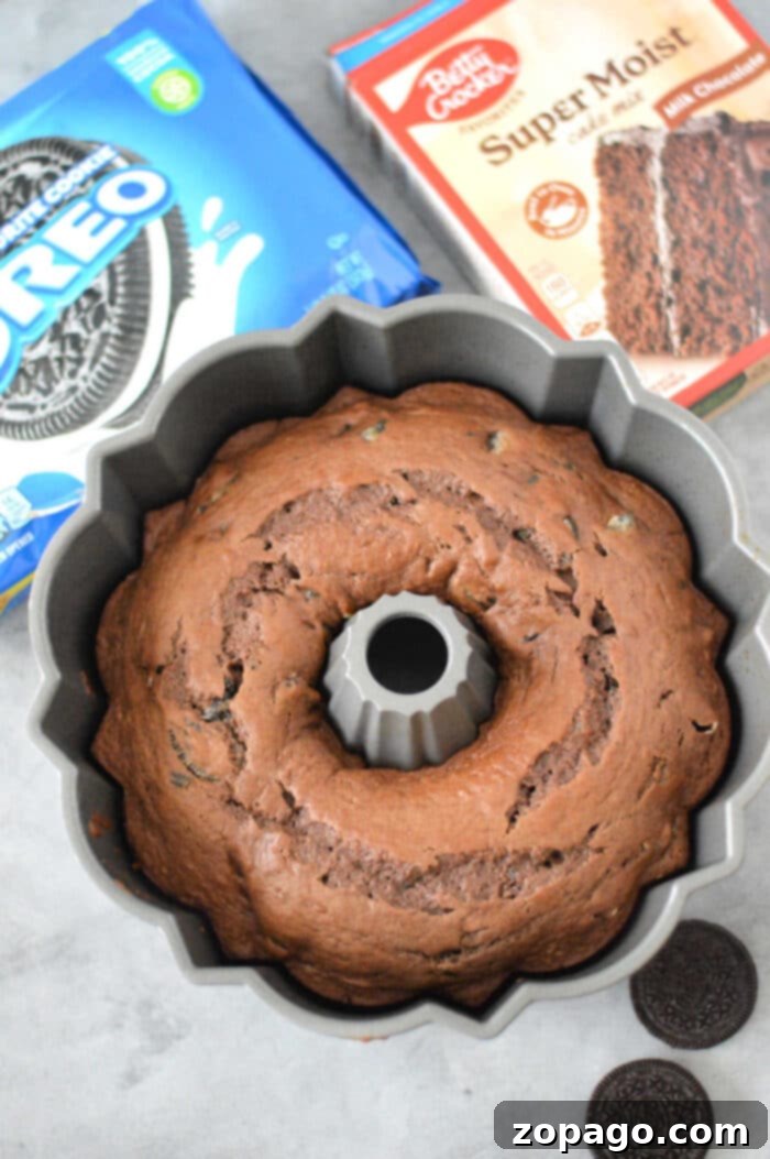 Cookies and Cream Bundt Delight 5 An Oreo Cake made with cake mix in a bundt pan, surrounded by whole Oreo cookies and cake mix boxes on a gray surface.