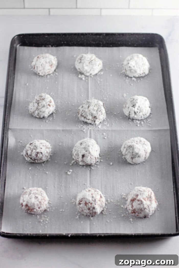 Dreamy Cool Whip Cake Cookies 5 Three chocolate Cool Whip crinkle cookies on a wire rack, dusted with powdered sugar.