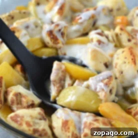 Cinnamon Swirl Peach Cobbler 6 A skillet of cinnamon rolls with peaches and cream, served with a black spoon, offers a delightful twist reminiscent of a cinnamon roll peach cobbler.