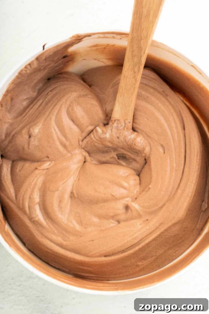 Easy Brownie Frosting 3 Delicate swirls of rich chocolate frosting elegantly adorn freshly baked brownies, showcasing the irresistible appeal of a perfectly frosted treat.