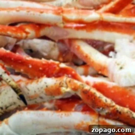 A pile of frozen red and white crab legs rests on ice, perfect for anyone curious about how to cook frozen crab legs to perfection.