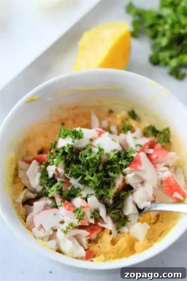 From Freezer to Feast: Perfect Frozen Crab Legs 7 A bowl of mixed ingredients, including chopped imitation crab meat and a sprinkle of chopped parsley on top.