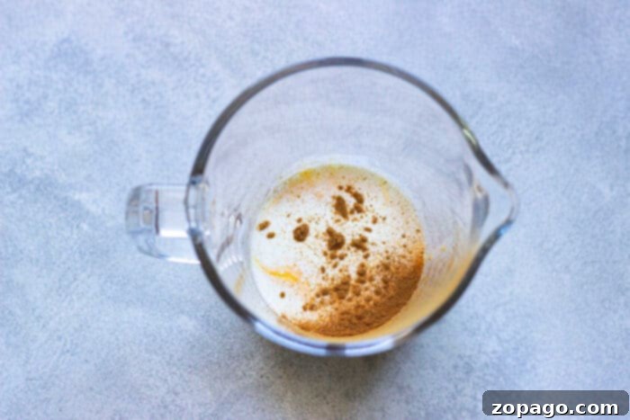 Spiced Pumpkin Cold Foam 5 A glass of iced coffee topped with pumpkin cold foam and a straw