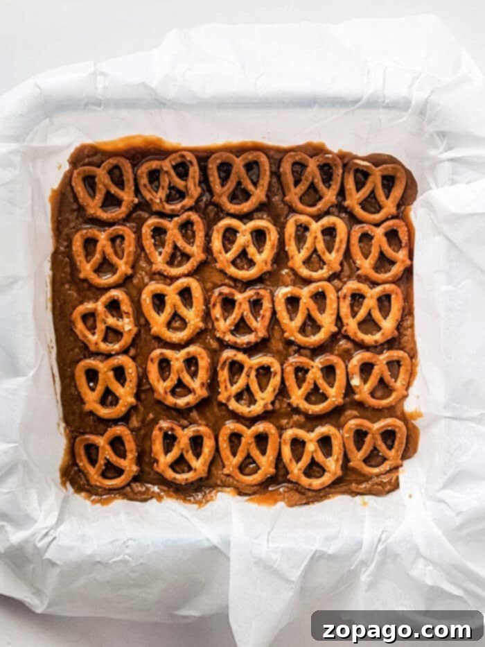Classic Peanut Butter Fudge 5 Square pan with Grandma's old fashioned topped with a grid of pretzels on parchment paper.