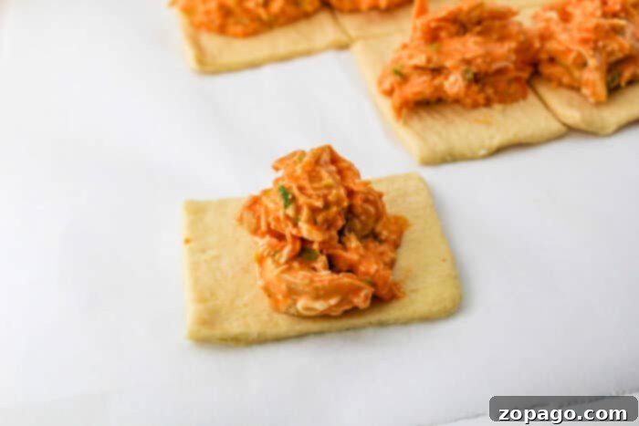 Crispy Buffalo Chicken Rolls 5 Assortment of stuffed crescent rolls, some golden brown, some with visible filling, on a baking tray.