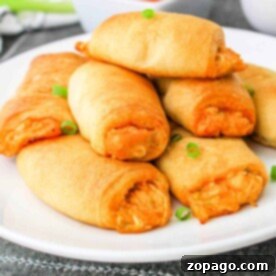 A plate of golden-brown Buffalo Chicken Rolls sits invitingly, with a dipping sauce in the background.