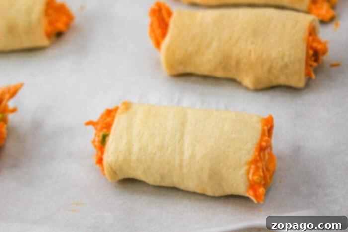 Crispy Buffalo Chicken Rolls 7 Close-up of a single Buffalo Chicken Roll, golden brown and perfectly baked, on a white surface.