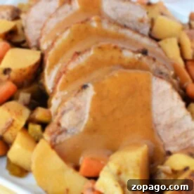 Tender Slow Cooker Eye of Round Roast 8 Sliced eye of round roast beef with gravy, nestled amongst an array of slow-cooked roasted potatoes, carrots, and root vegetables.
