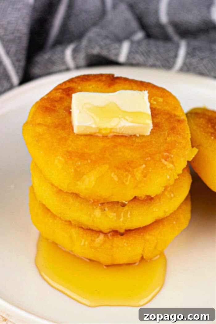 Crispy Cornbread Cakes 6 A stack of golden hot water cornbread with butter and syrup