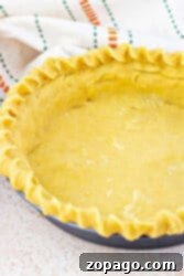 Buttery Shortbread Pie Crust 10 Unbaked shortbread pie crust in a pan with fluted edges, resting on a light surface beside a striped cloth.