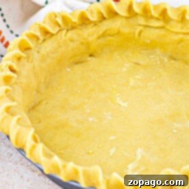 Buttery Shortbread Pie Crust 6 Unbaked shortbread pie crust in a pan with fluted edges, resting on a light surface beside a striped cloth.