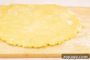 Buttery Shortbread Pie Crust 8 Round sheet of shortbread pie crust dough on a floured wooden surface, ready for baking or cutting.