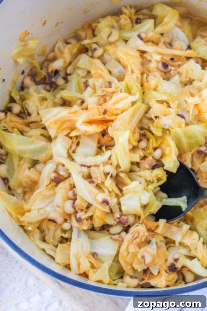 Black-Eyed Peas and Cabbage: A Hearty Southern Classic 6 A savory pot of Black Eyed Peas and Cabbage awaits, complete with a spoon, inviting a taste.