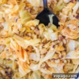 A close-up of black-eyed peas and tender cabbage cooked to perfection, with a spoon resting invitingly in the pot.