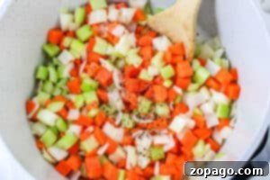 Hearty Corned Beef and Cabbage Bowl 8 Chopped carrots, celery, and onions are stirred with a wooden spoon in a white pot—the flavorful base for hearty Corned Beef and Cabbage Soup.