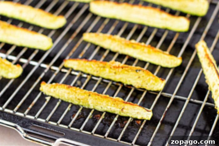 Roast Zucchini Perfectly Every Time 5 Close-up of golden brown zucchini fries on a baking sheet, showcasing perfect roasting for a crispy texture.