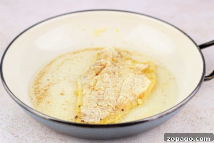 Golden Pan Fried Swai 4 Fried Swai Fish fillet, perfectly coated in corn flour, sizzles in a butter-filled pan.