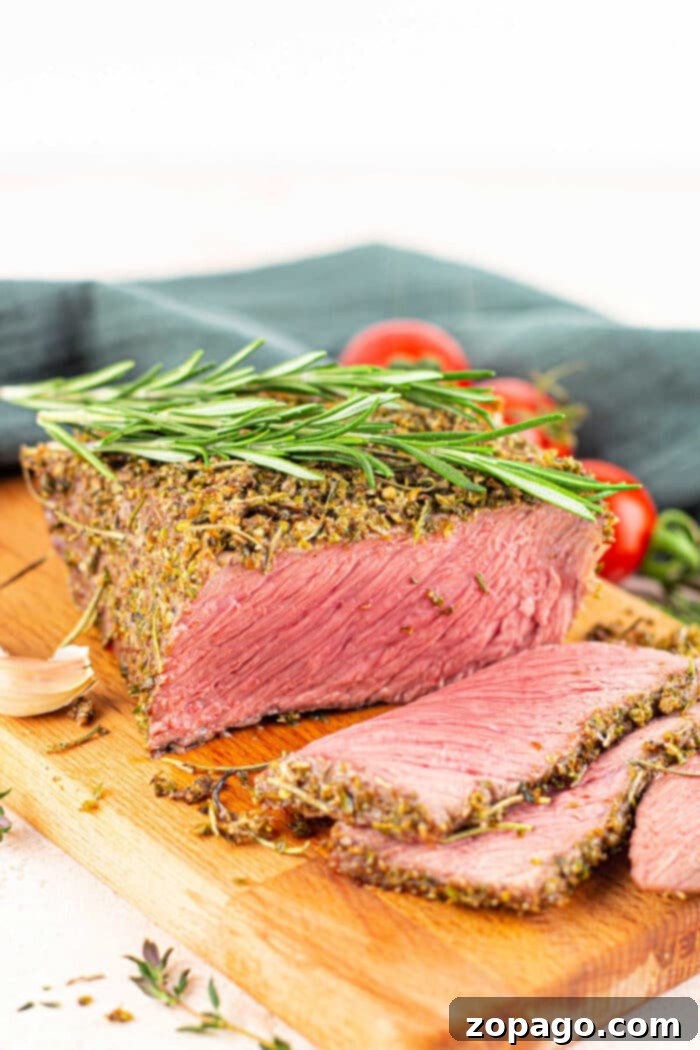 Tender Bottom Round Roast Made Easy 8 A complete dinner plate featuring a sliced Bottom Round Roast, garnished with herbs and served with gravy and roasted vegetables.