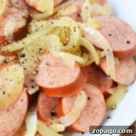 Sliced kielbasa and onions seasoned with black pepper, a simple and hearty slow cooker meal.