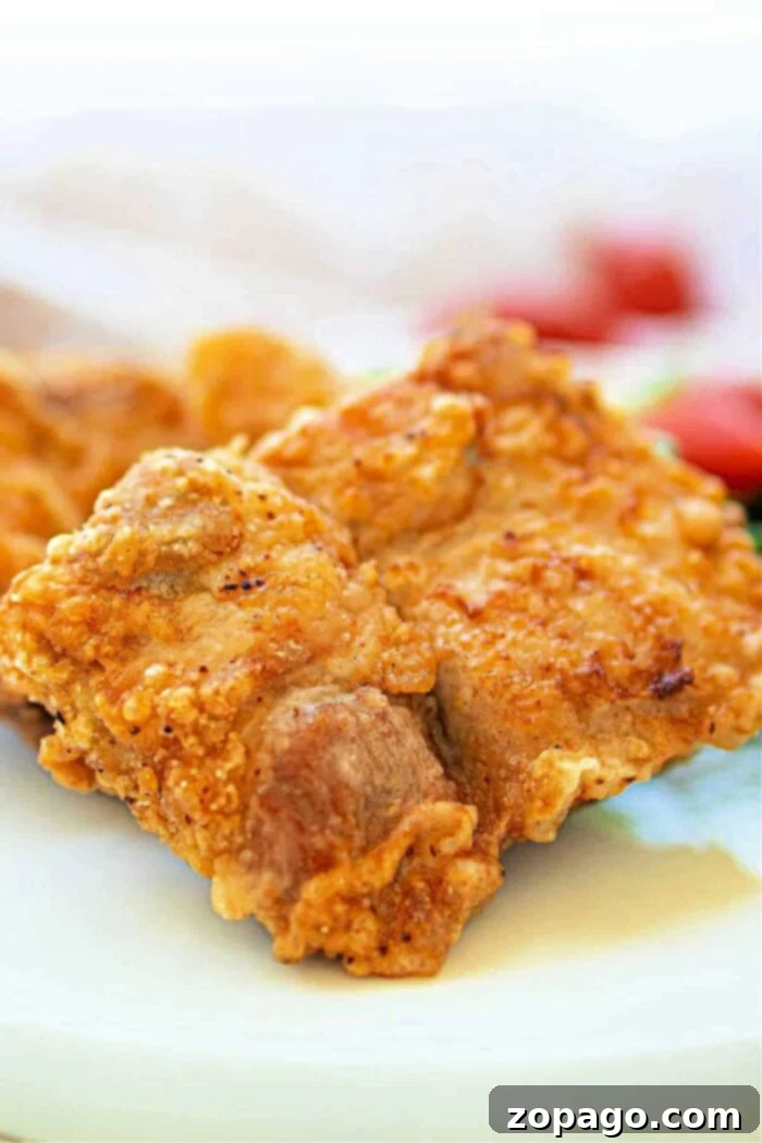 Golden Crispy Pork Chops 2 Close-up of a golden, crispy fried pork chops nestled on a white plate, reminiscent of the crunch youd find in perfectly deep-fried pork chops.
