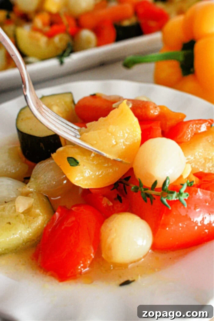 Effortless Slow Cooker Vegetables 2 A close-up of a plate with cooked vegetables, including cherry tomatoes, onions, and slices of zucchini. A fork is picking up a piece of yellow pepper. A yellow bell pepper and more slow cooker vegetables are visible in the background.