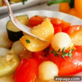 Effortless Slow Cooker Vegetables 8 A close-up of a plate with cooked vegetables, including cherry tomatoes, onions, and slices of zucchini. A fork is picking up a piece of yellow pepper. A yellow bell pepper and more slow cooker vegetables are visible in the background.