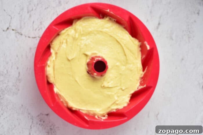Ultimate Sock It To Me Cake with Cake Mix 5 A vibrant red bundt pan filled with golden-yellow cake batter, awaiting its transformation into a scrumptious Sock It to Me cake.