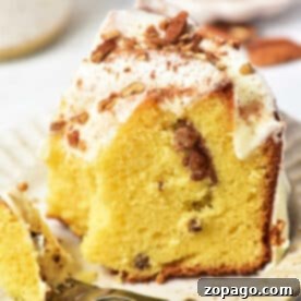 Ultimate Sock It To Me Cake with Cake Mix 7 A slice of Sock It to Me cake, made with a delightful cake mix, sits on a plate with frosting and nuts, accompanied by a fork.