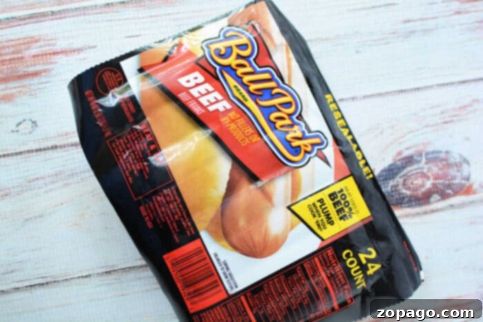 Rapid Slow Cooker Hot Dogs 4 A package of Ball Park brand beef hot dog buns sits on a wooden surface. The packaging shows hot dogs and reads "BEEF - Made with 100% Beef Hot Dogs." Perfect for making slow cooker hot dogs, the package contains 24 individually wrapped hot dogs.