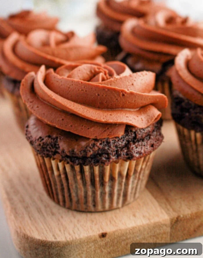 Effortless Brownie Cupcakes 2 Brownie cupcakes with swirled frosting are artfully arranged on a wooden board, creating an irresistible treat.