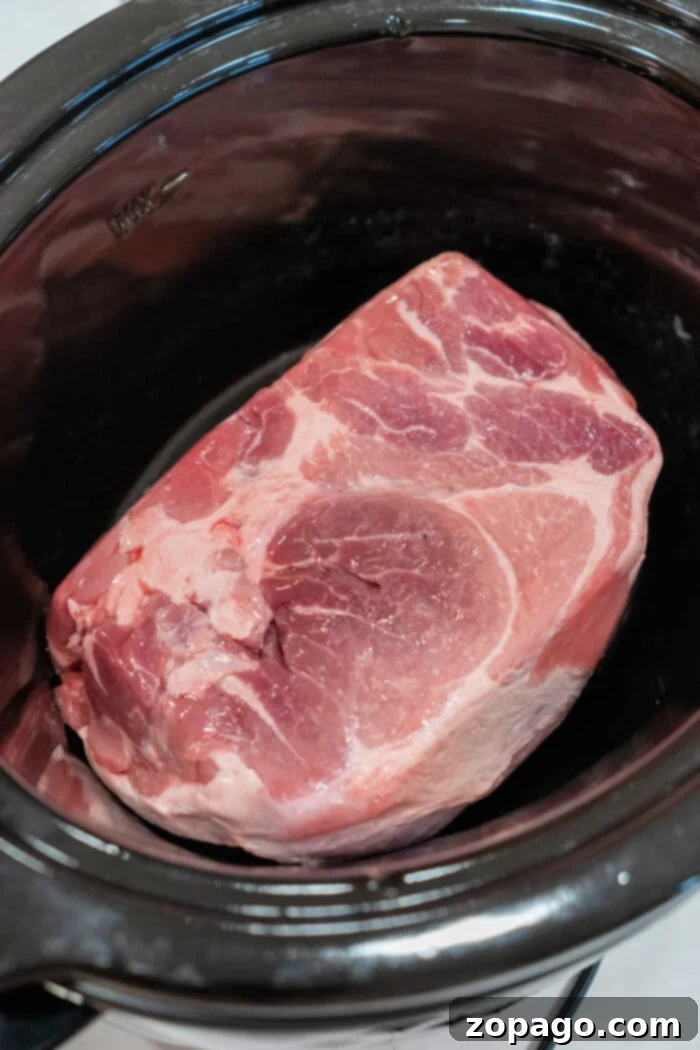 The Easiest 2-Ingredient Pulled Pork 4 A large raw pork roast set inside a slow cooker is the perfect start to an easy pulled pork recipe.