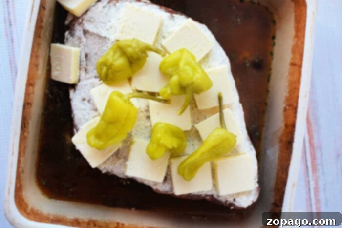 Slow Cooker Mississippi Pot Roast 5 This Mississippi pot roast features a beef roast in a baking dish, topped with butter slices and pepperoncini peppers, creating a flavorful and tender recipe perfect for any occasion.