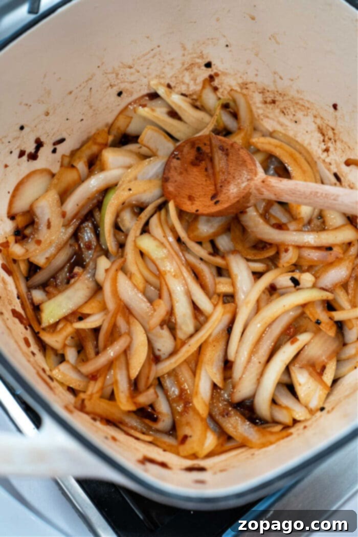 Slow-Cooked Pot Roast with Caramelized Onions 5 Sliced onions roasting in a pot, seasoned to perfection and stirred with a wooden spoon.