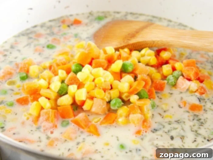 Quick & Cozy Chicken Pot Pie 9 Simple chicken pot pie filling recipe, being stirred with a wooden spoon.