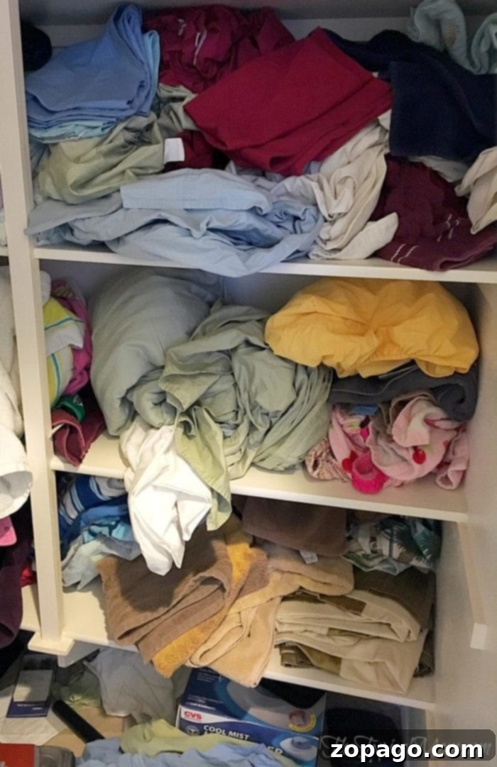 Practical and free tips for organizing your linen closet, saving you considerable time and effort. Before image of a disorganized linen closet, showcasing a jumbled mess of sheets and towels. This photo highlights the common challenge of linen closet organization.