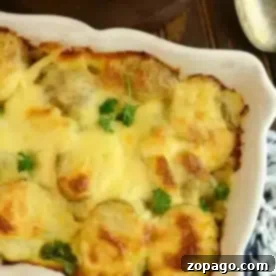 Simple Au Gratin Potatoes 3 A baking dish with easy potatoes au gratin, topped with a cheesy crust and garnished with parsley, sits on a wooden table alongside a serving spoon and plates.