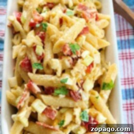 Dreamy Creamy Pasta Salad 4 Creamy pasta salad with mayo, penne, diced tomatoes, bacon, and herbs in a rectangular dish on a checkered cloth.