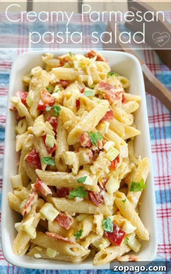 Creamy pasta salad that's a great side dish for any bbq or potluck. Simple creamy parmesan pasta salad recipe you can load up with anything. #pasta #salad #easy #creamy Close-up of a serving of creamy pasta salad in a small dish, showing penne, vegetables, and dressing.