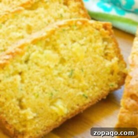 Close-up of sliced zucchini pineapple bread on a wooden surface, with a blue floral towel in the background.