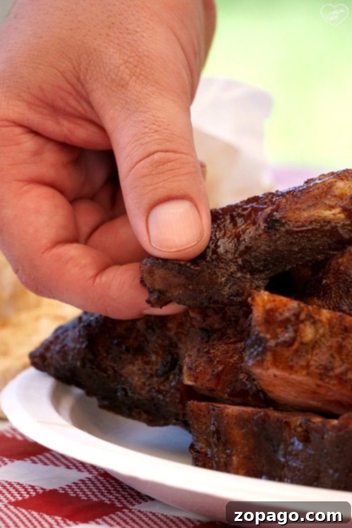 Discover the secret to making the best fall-off-the-bone barbecue ribs recipe every time. A full rack of tender, glazed barbecue ribs on a cutting board, ready to be sliced and served.