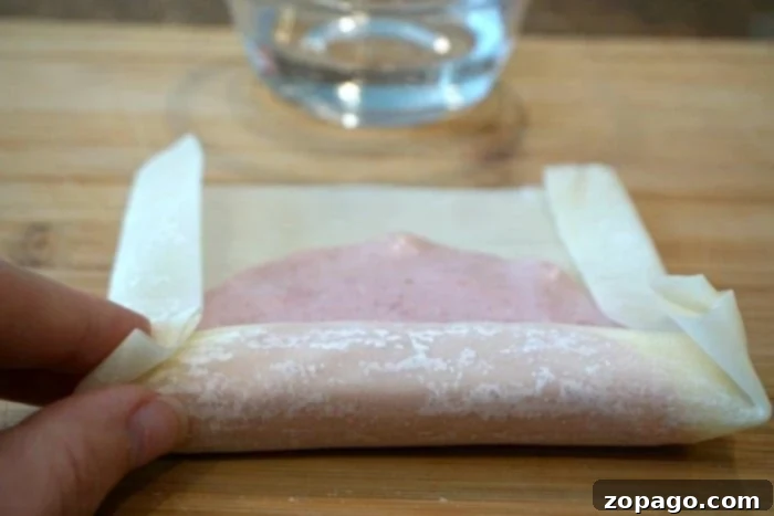 Crispy Ham and Cheese Egg Rolls 4 A tray of freshly rolled ham and cheese egg rolls, perfectly sealed and ready for cooking.