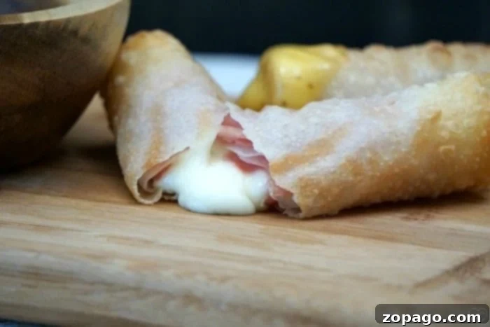 Crispy Ham and Cheese Egg Rolls 5 A vibrant close-up of a perfectly fried ham and cheese egg roll, glistening with a golden crisp.